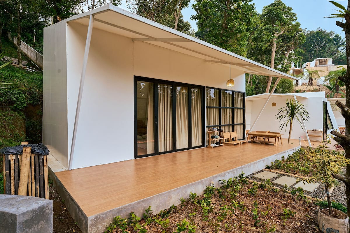 Une maison moderne dotée d’une terrasse en bois, de grandes portes-fenêtres coulissantes et d’un patio couvert.