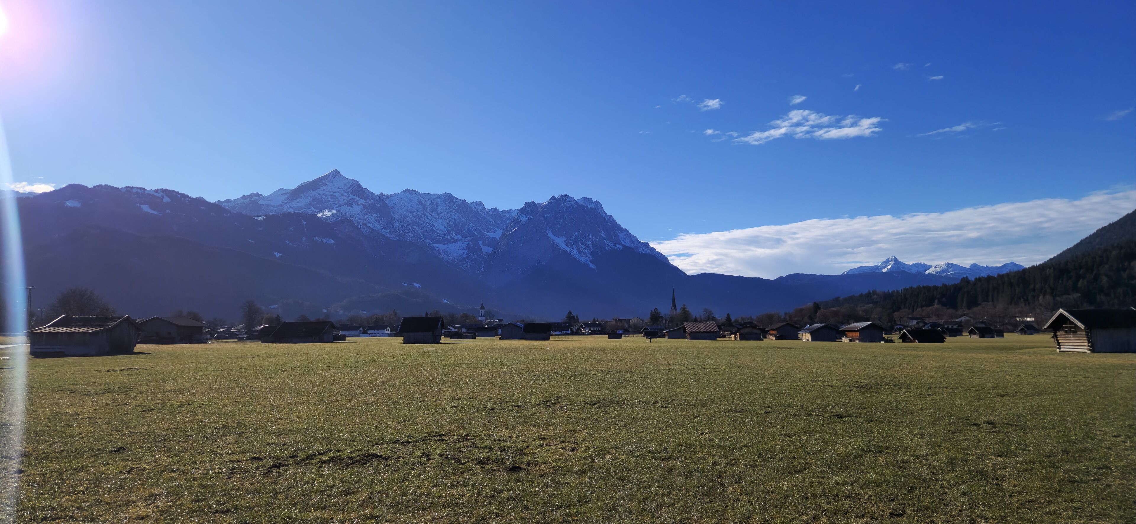 A rural landscape with mountains, a clear sky, and several small houses.