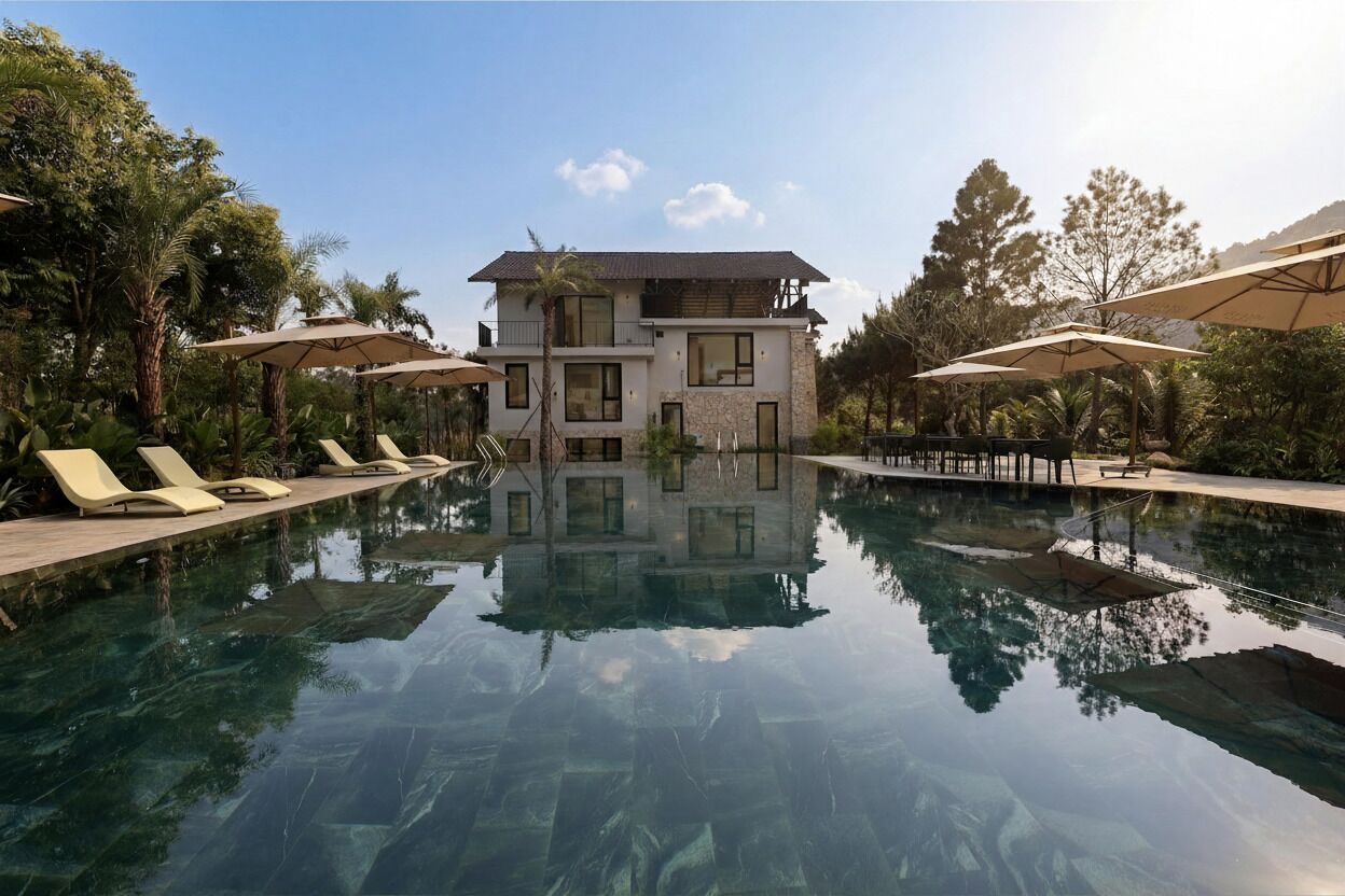 Un hotel moderno con piscina, lettini e ombrelloni.