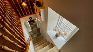 A staircase with wooden balusters, carpeted steps, and a window with a view. - Peak District Retreat · Hope Valley · Dogs Welcome (Stoney Middleton)