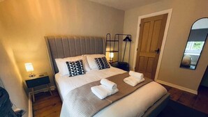 A bedroom with a bed, bedside tables, a mirror, and a door. - Peak District Retreat · Hope Valley · Dogs Welcome (Stoney Middleton)