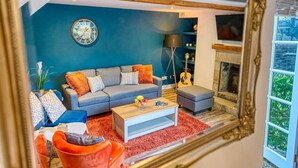 A living room with a blue wall, a grey sofa, a coffee table, and a fireplace. - Stylish Bakewell Cottage with Free Parking (Bakewell)