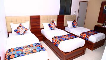 Habitación de hotel con tres camas, cada una con una colcha estampada y almohadas a juego.