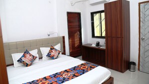 A bedroom with a bed, a wooden wardrobe, a desk, and a window. - JMC HOTEL KIA INN (Pithampur)