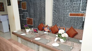 A reception area with a long counter, multiple seating options, and a decorative wall. - JMC HOTEL KIA INN (Pithampur)