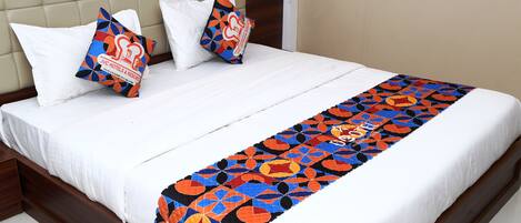 A bed with a white mattress, a brown headboard, and a colorful quilt.