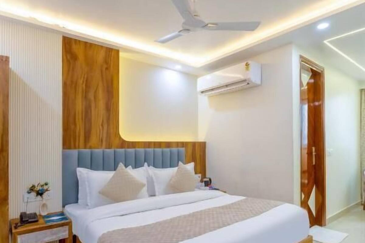 Une chambre d’hôtel moderne dotée d’un grand lit, d’un ventilateur de plafond, d’un appareil de climatisation et d’un mur décoratif en bois.