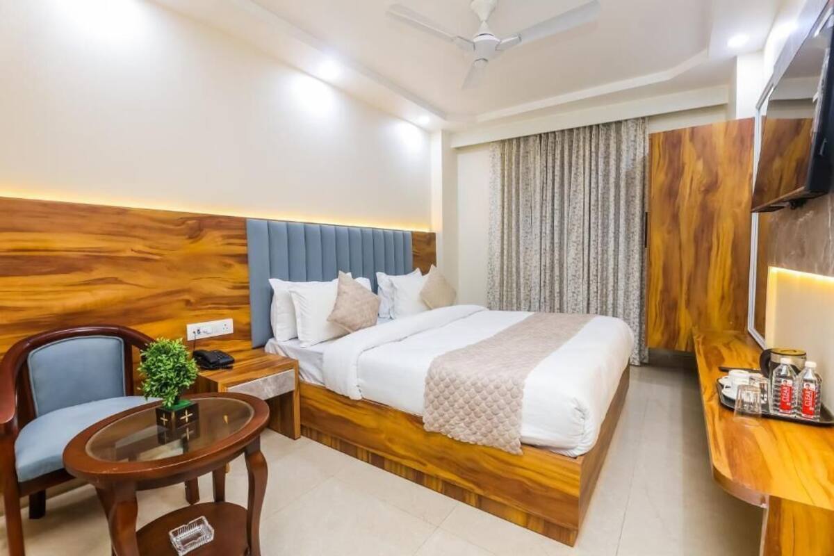 Une chambre d’hôtel comprenant un lit, un bureau, une chaise, une petite table avec une plante et un téléviseur.