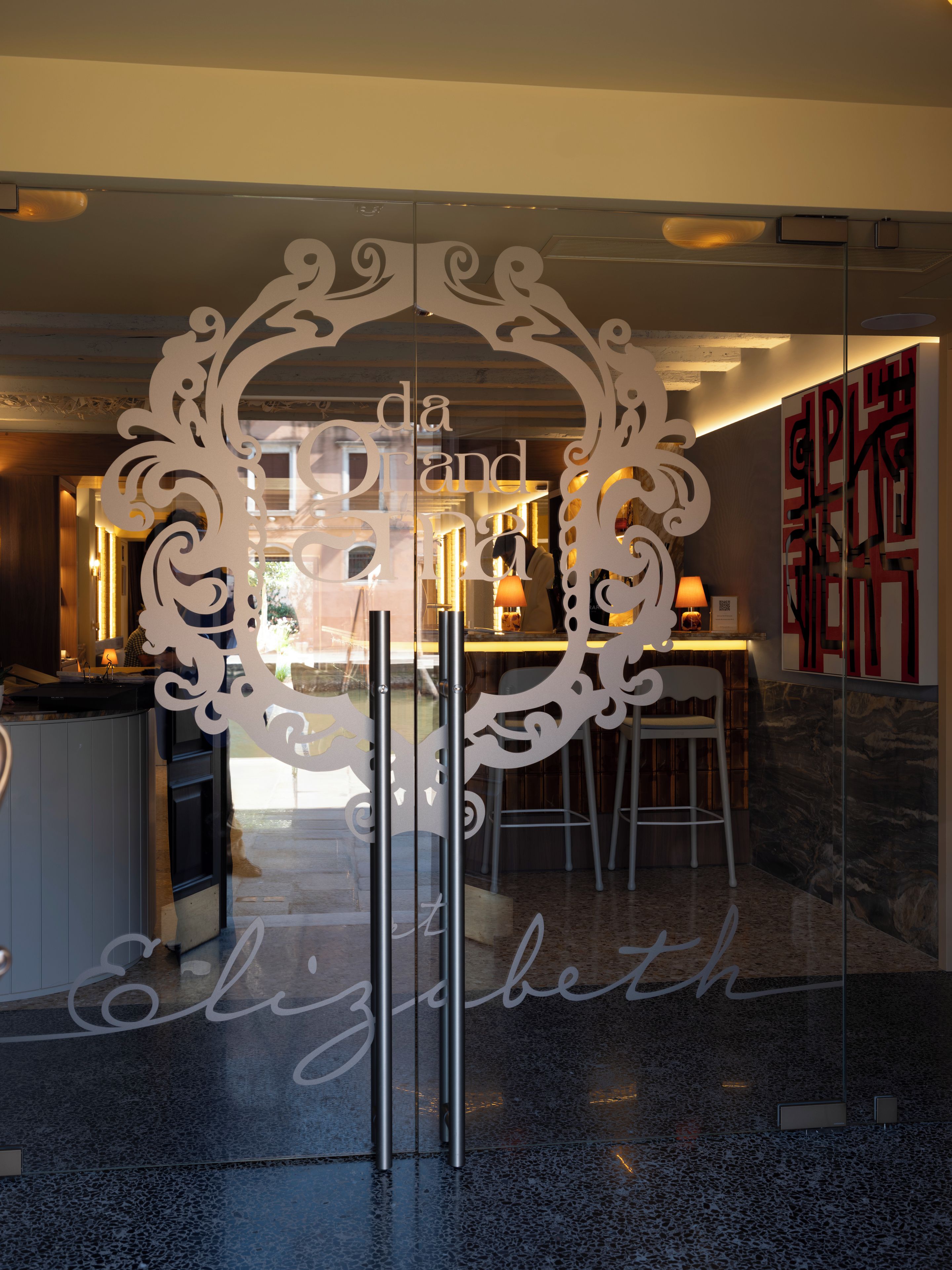 Un interior moderno con un separador de vidrio que presenta letras recortadas decorativas que deletrean 'da Grand Elizabeth'.