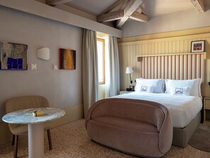 A hotel room with a bed, a round table, a chair, a lamp, and artwork on the walls. -  Elizabeth Unique Venice a Member of Design Hotels (Venice)
