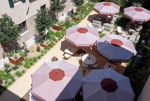 An outdoor patio area with multiple umbrellas, seating arrangements, and planters. -  Elizabeth Unique Venice a Member of Design Hotels (Venice)