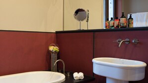 A bathroom with a white sink, a round mirror, and toiletries on the counter. -  Elizabeth Unique Venice a Member of Design Hotels (Venice)