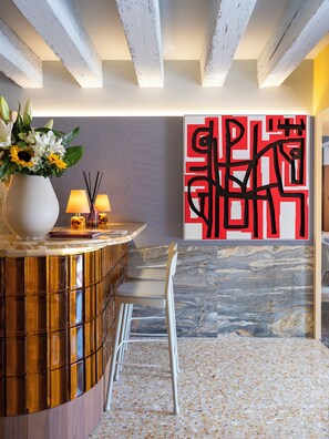 A modern reception area with a marble floor, a gold reception desk, and a large abstract art piece on the wall. -  Elizabeth Unique Venice a Member of Design Hotels (Venice)