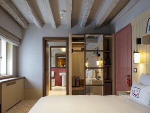 Habitación de hotel con una cama grande, un armario, un baño con lavamanos y vistas al pasillo.