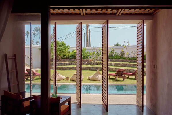A room with a view of a swimming pool, outdoor seating, and a pergola structure. - UNU Boutique Hotel (Ahangama)