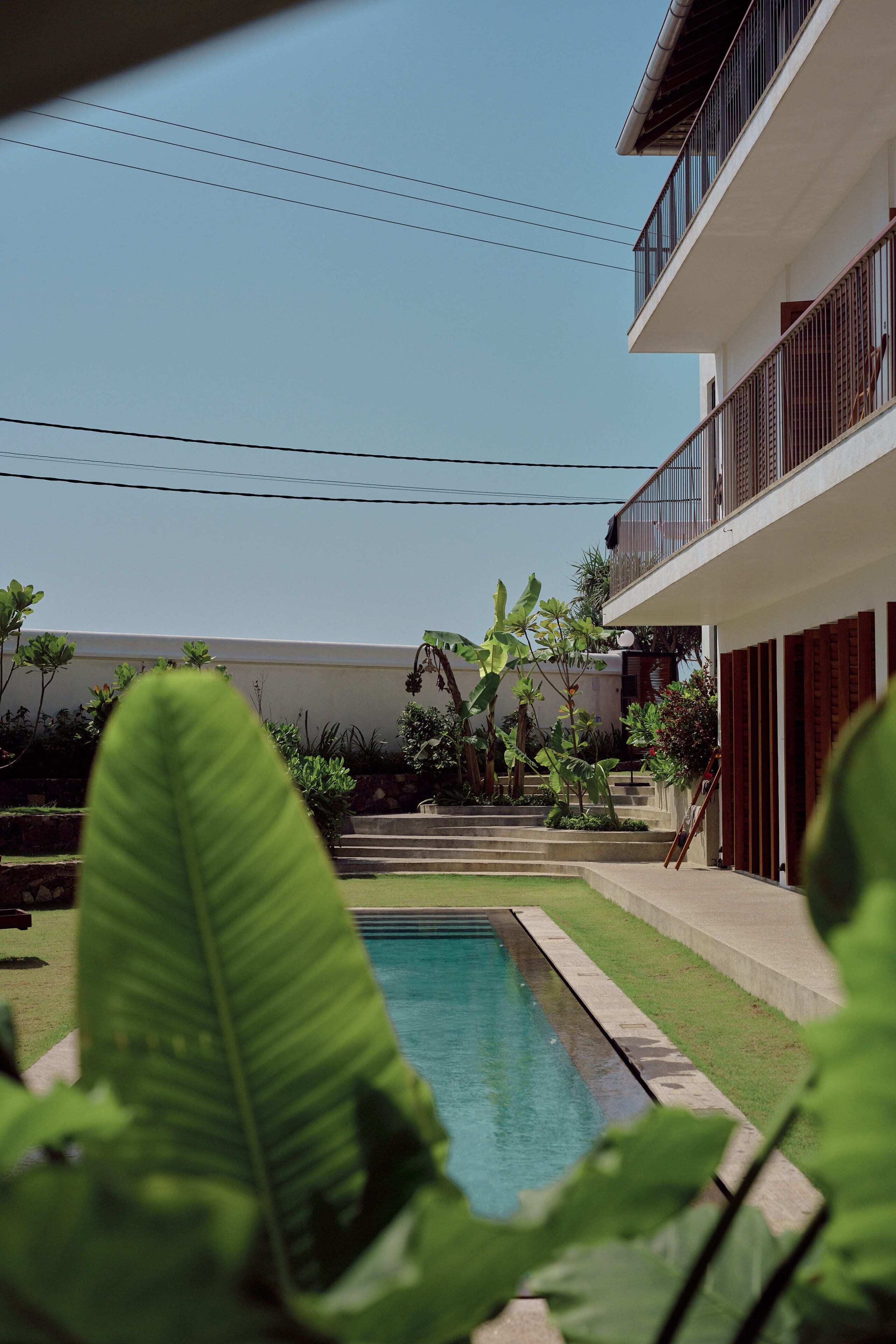 A swimming pool, a two-story building with balconies, and surrounding greenery.