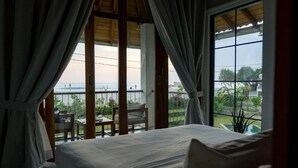 A bedroom with a large bed, a balcony with a table and chairs, and a view of the beach. - UNU Boutique Hotel (Ahangama)