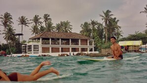 A beachfront property with a pool, palm trees, and a building with a tiled roof. - UNU Boutique Hotel (Ahangama)