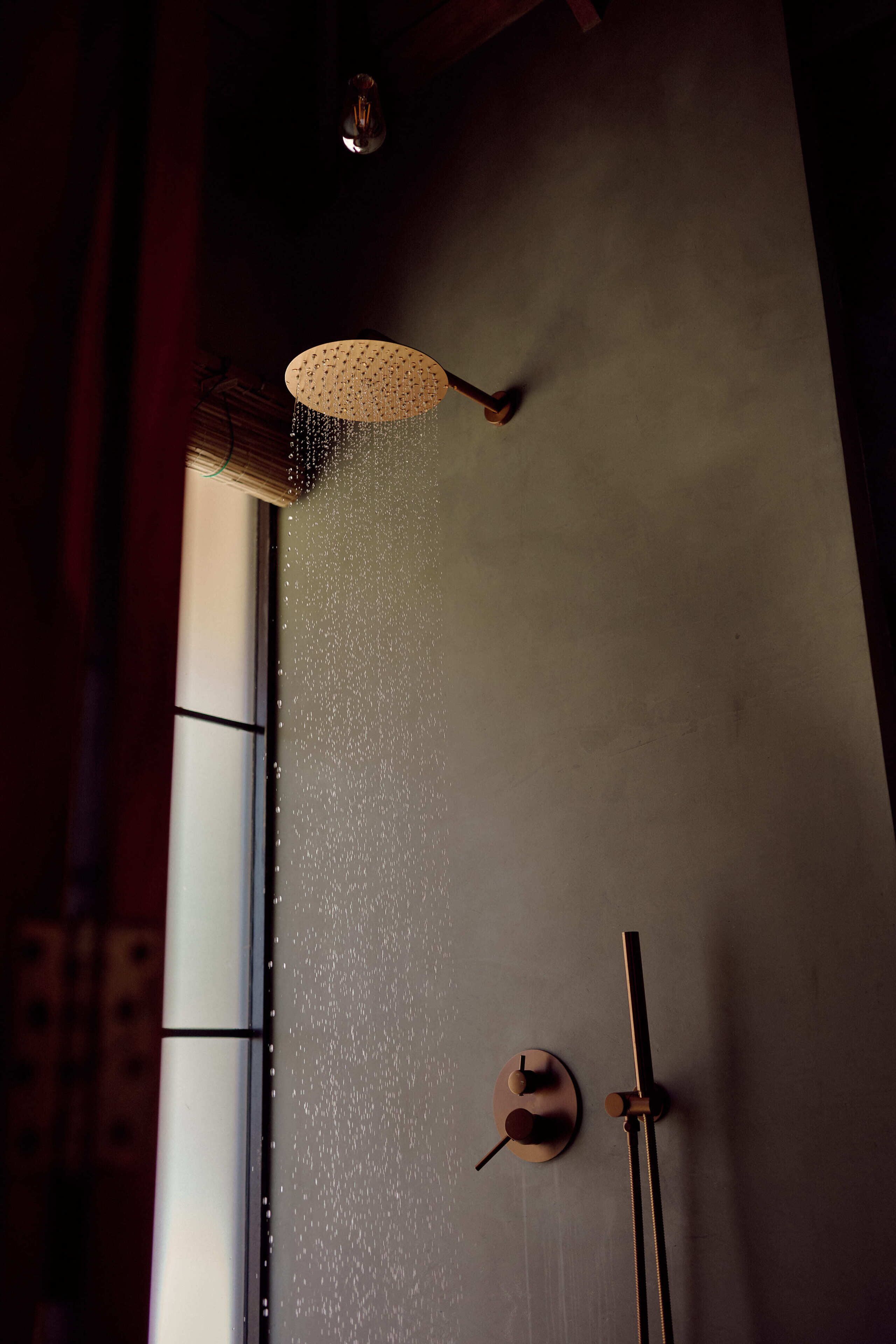 Ducha con un diseño de cascada, toallero de pared y ventana con persianas.