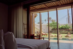 Une chambre d’hôtel avec un lit, une vue sur la piscine et un balcon aménagé avec des sièges.