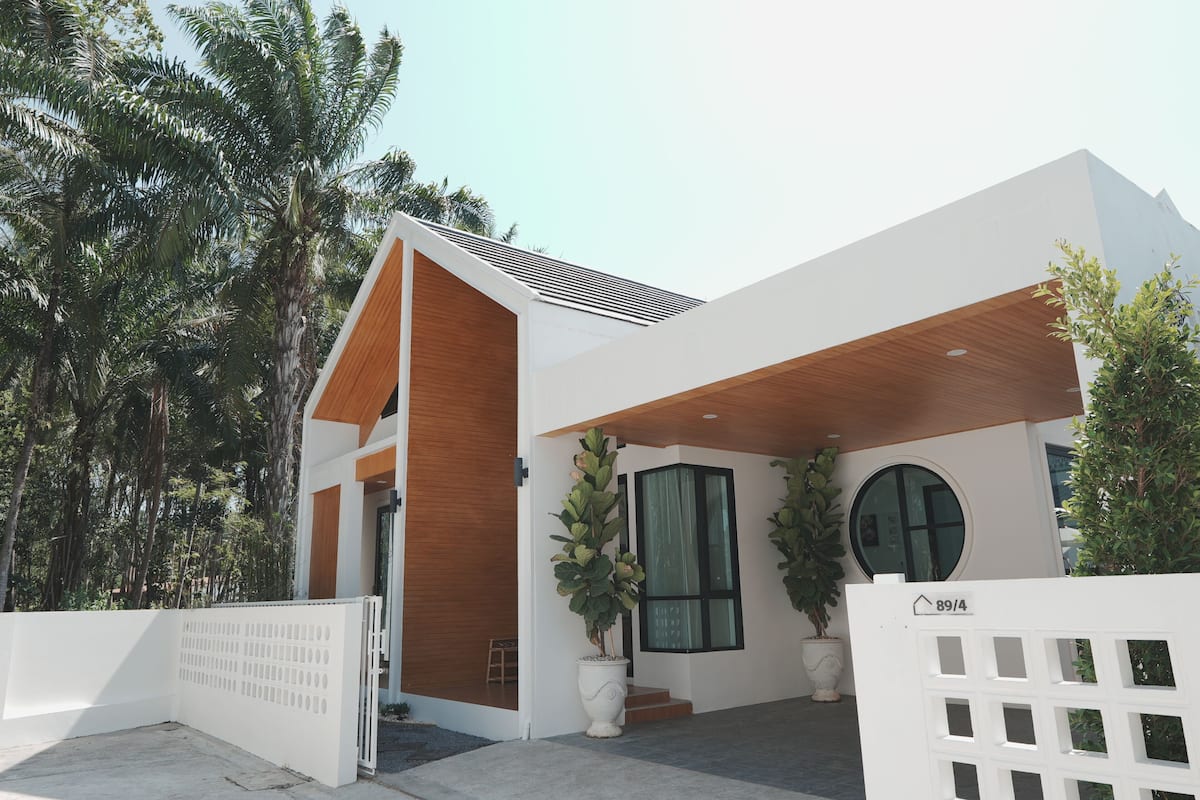 A modern building with a white facade, a wooden sloped roof, and a circular window.