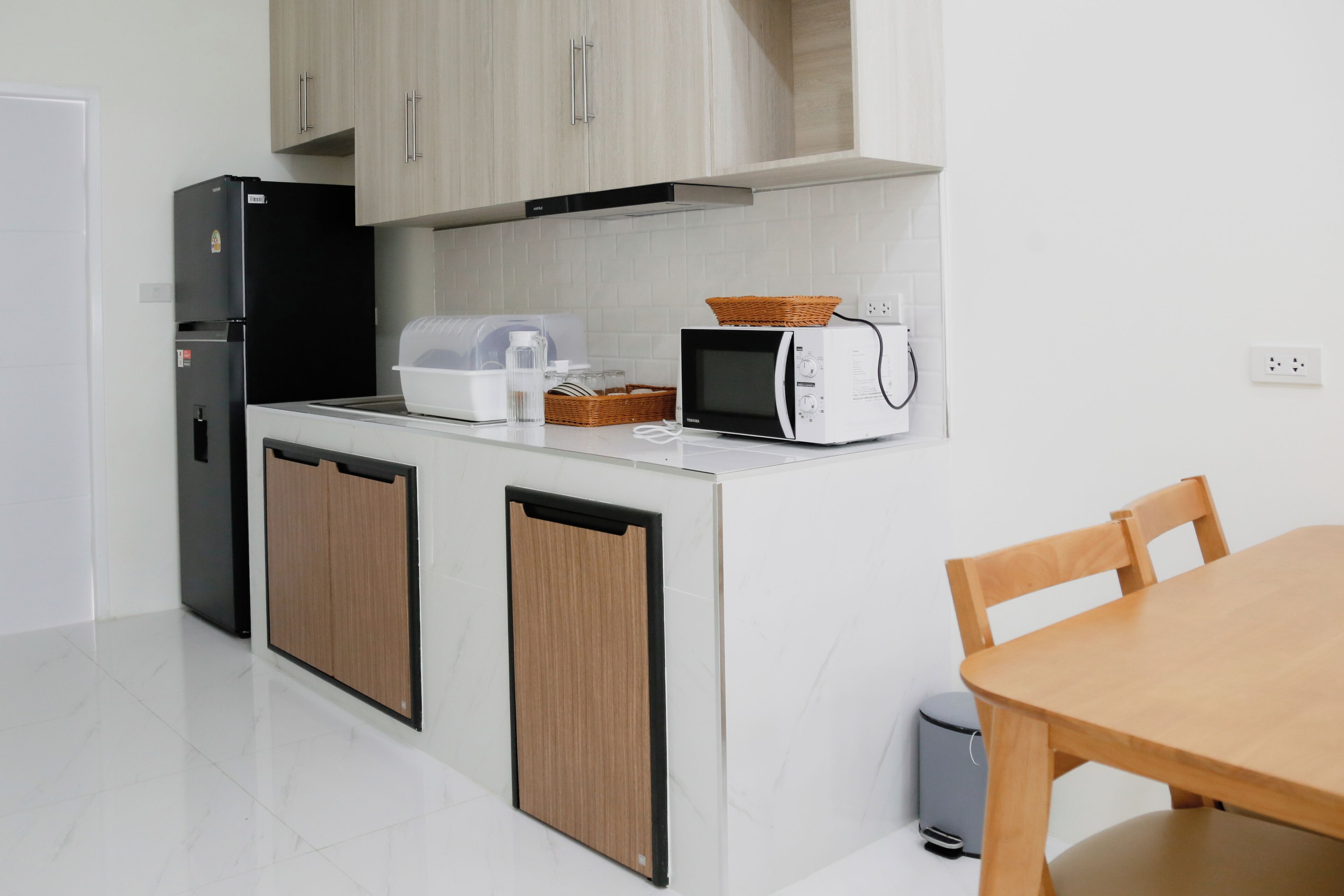 Una cucina compatta con frigorifero, forno a microonde e un piccolo tavolo con sedie.