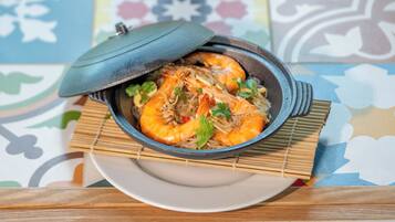 Un bol de camarones cocidos con una tapa, sobre un plato con una estera de bambú debajo.
