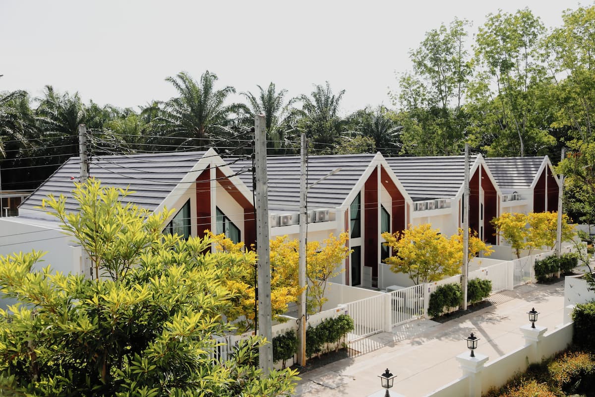 A row of modern buildings with a sloped roof, surrounded by lush greenery and trees.