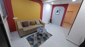 A living room with a sofa, a coffee table, and a patterned rug. - Urban Stay Home (Pune)
