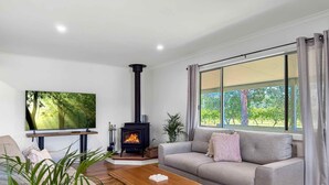 Un salon moderne avec une cheminée, un canapé, une table basse et une grande fenêtre avec des rideaux.