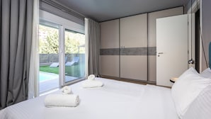 Habitació d'hotel amb llit, una finestra gran amb cortines, una porta corredissa i vista a la piscina i vegetació exterior.