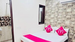 A bedroom with a bed, a ceiling fan, a stone wall, and an air conditioning unit.