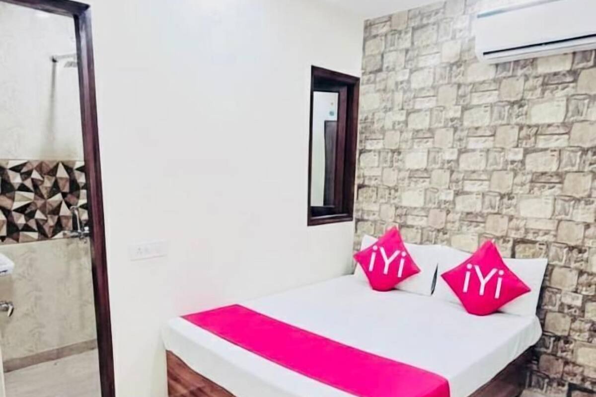 A bedroom with a bed, a ceiling fan, a stone wall, and an air conditioning unit.