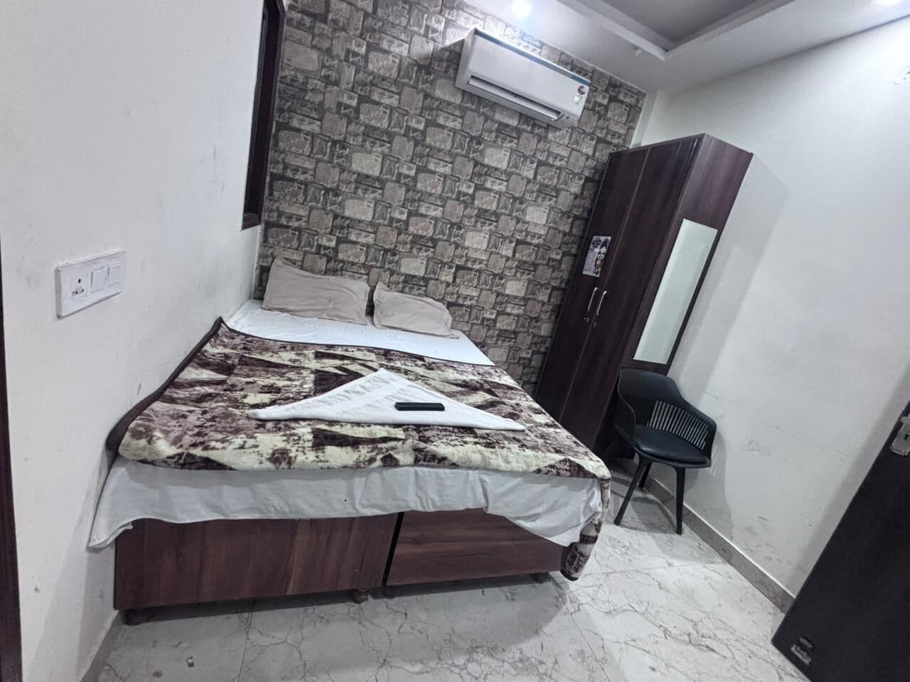 Une chambre à coucher comprenant un lit, une armoire, une chaise et un climatiseur fixé au mur.