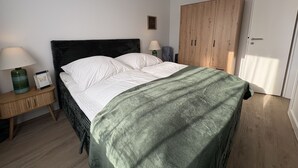 Een slaapkamer met een bed, nachtkastjes, een kledingkast en een hanglamp.