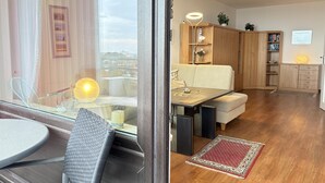 Ett modernt vardagsrum med ett matbord i glas, en soffa, träskåp och en röd, mönstrad matta.