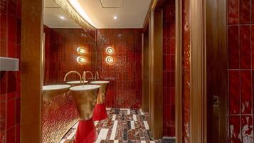 A modern bathroom with red marble walls, gold fixtures, and a checkered floor.