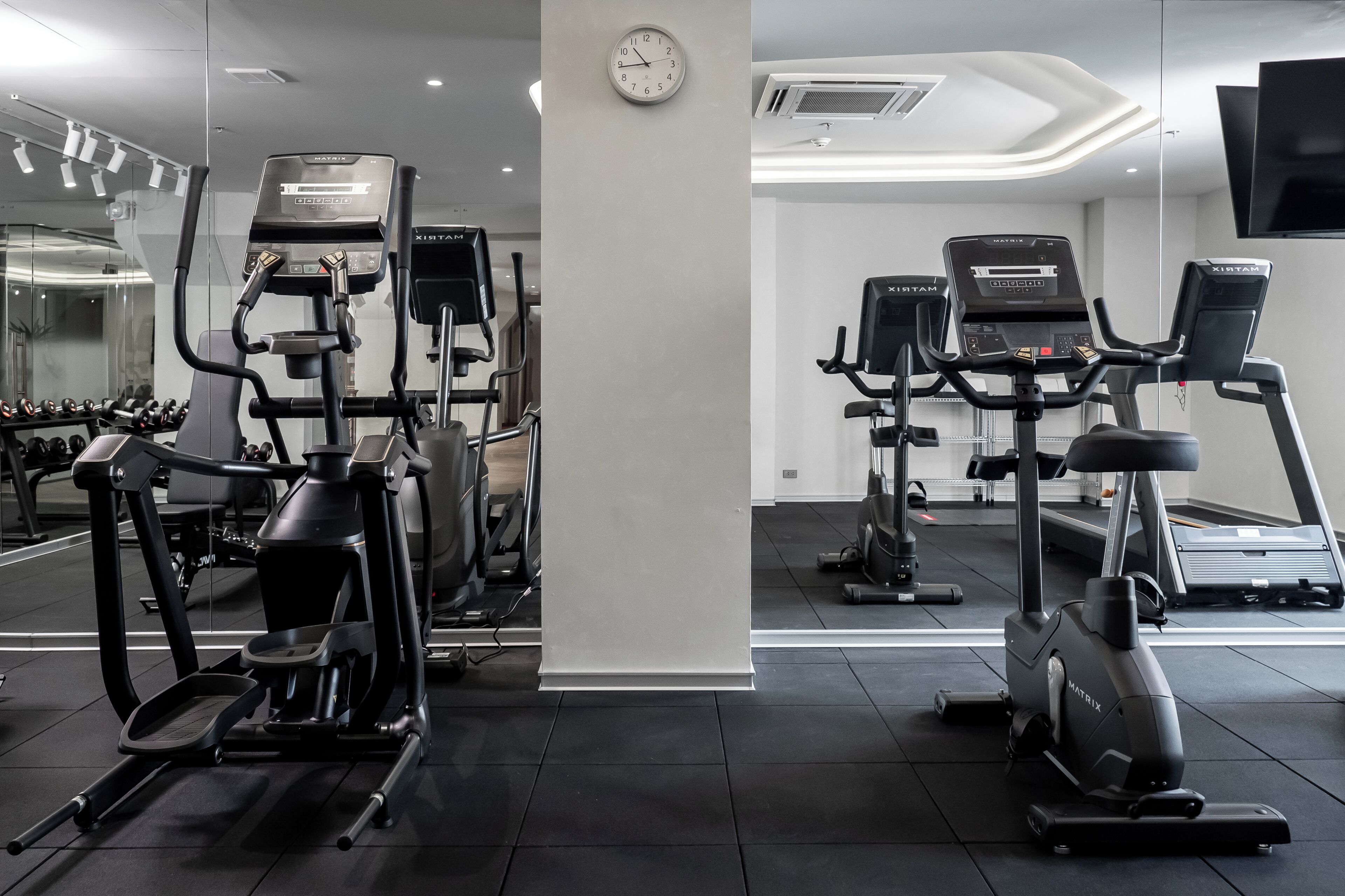 Une salle de sport équipée de tapis de course, de vélos elliptiques et de poids libres.