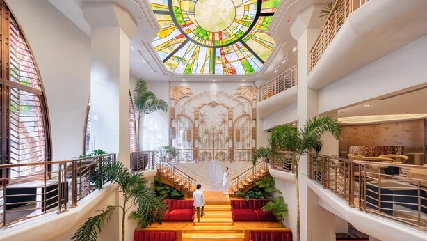 A multi-level interior with a central staircase, railings, and potted plants.