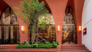 A hotel entrance with arched doorways, a tree, and steps leading up to the entrance.