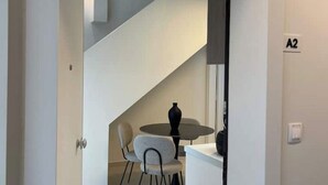 Ein modernes Interieur mit einer Treppe, einem Essbereich mit Tisch und Stühlen sowie einer Wand mit dem Schriftzug 'A2'.