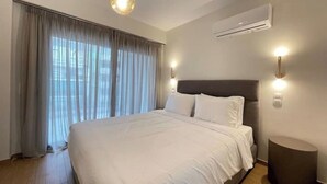 Ein Schlafzimmer mit einem großen Bett, einer Deckenleuchte, einer Klimaanlage und einem Fenster mit Vorhängen.