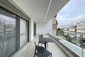 Een balkon met een tafel en stoelen, grote ramen en uitzicht op de stadszicht.