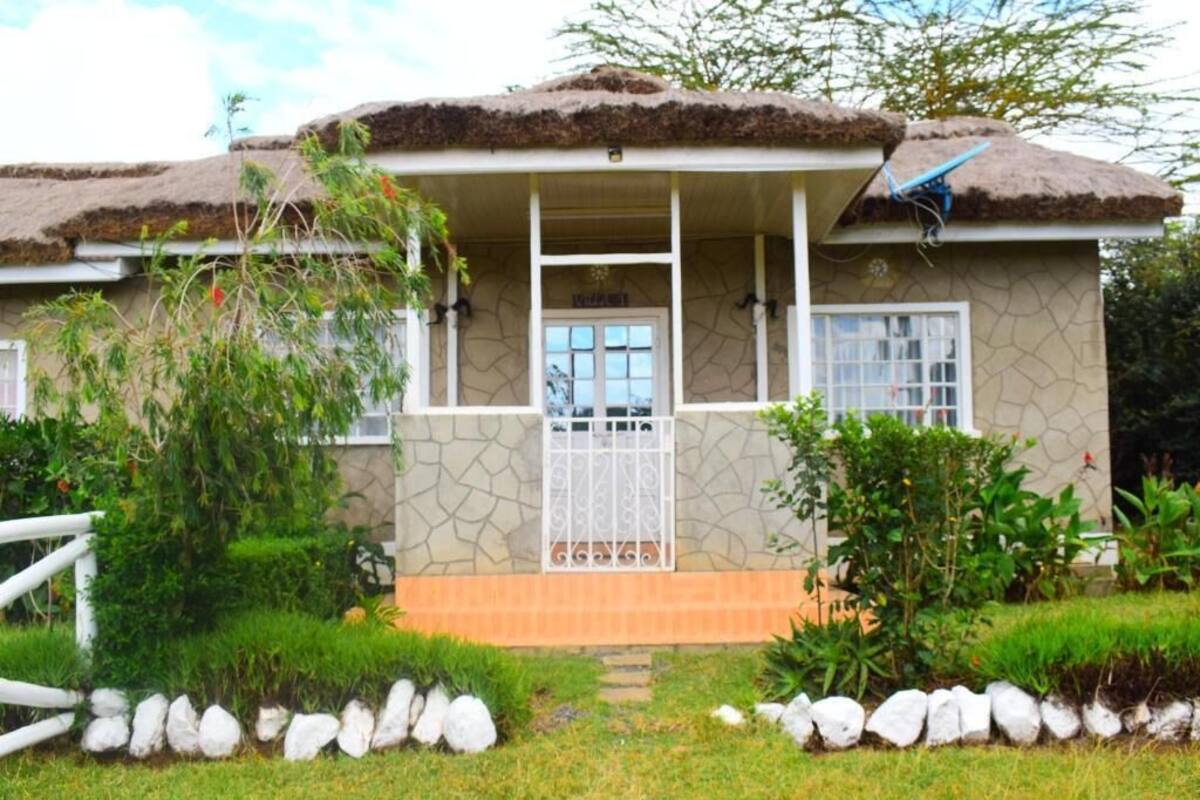 Una casa con techo de paja, fachada de piedra y un pequeño porche con barandilla blanca.