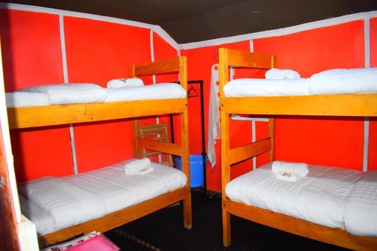 Dormitorio con literas, paredes rojas y ropa de cama blanca.