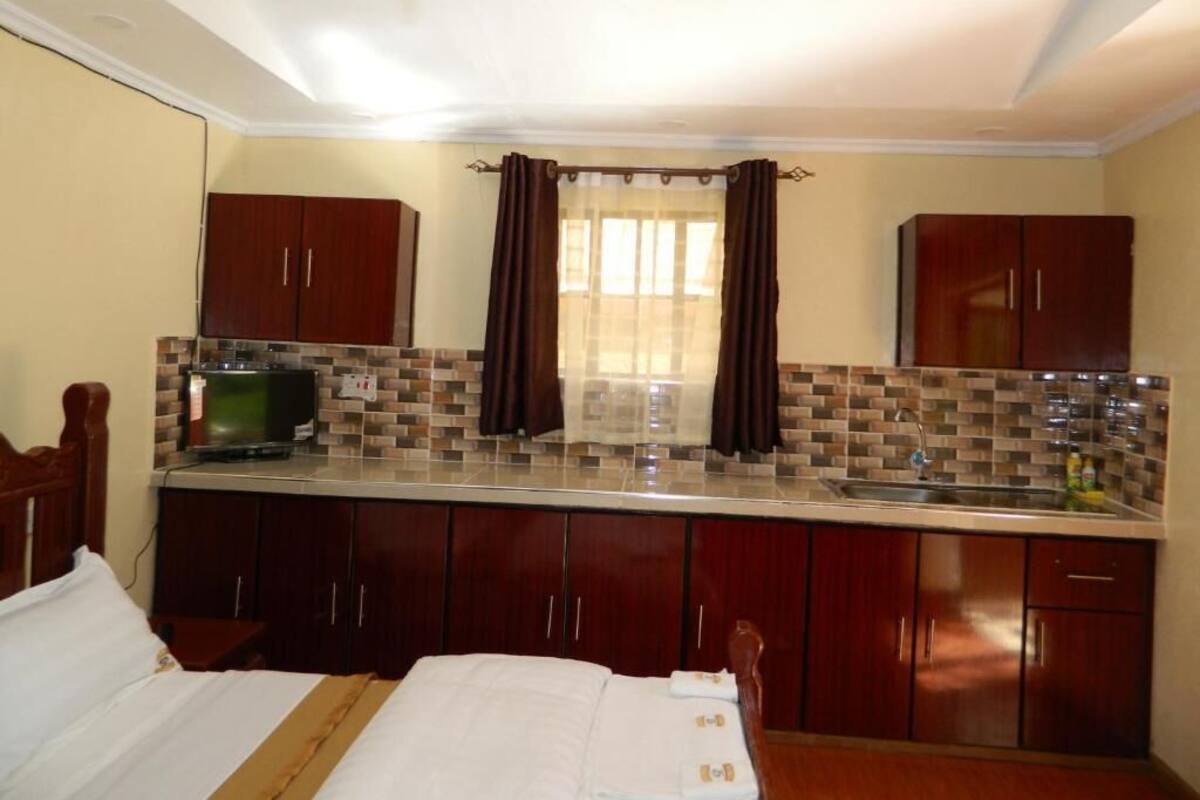 Una habitación de hotel pequeña con cama, kitchenette y baño.