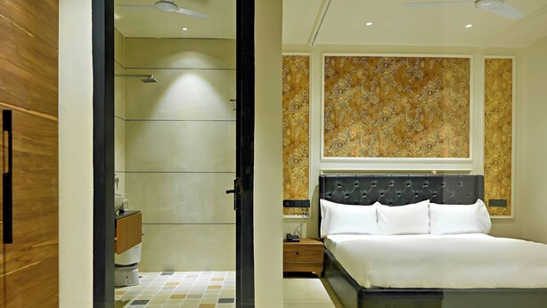 Une chambre d’hôtel comprenant un lit, une table de chevet, une armoire en bois et une salle de bain avec douche.