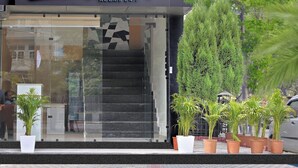 L’entrée d’un hôtel, avec une enseigne indiquant « Hébergement chez l’habitant – Café 9 », et un escalier menant à l’intérieur.
