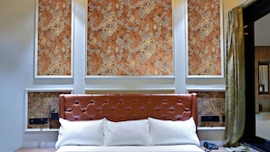 Une chambre à coucher moderne avec un lit, un ventilateur de plafond, des motifs décoratifs sur les murs et une fenêtre avec des rideaux.