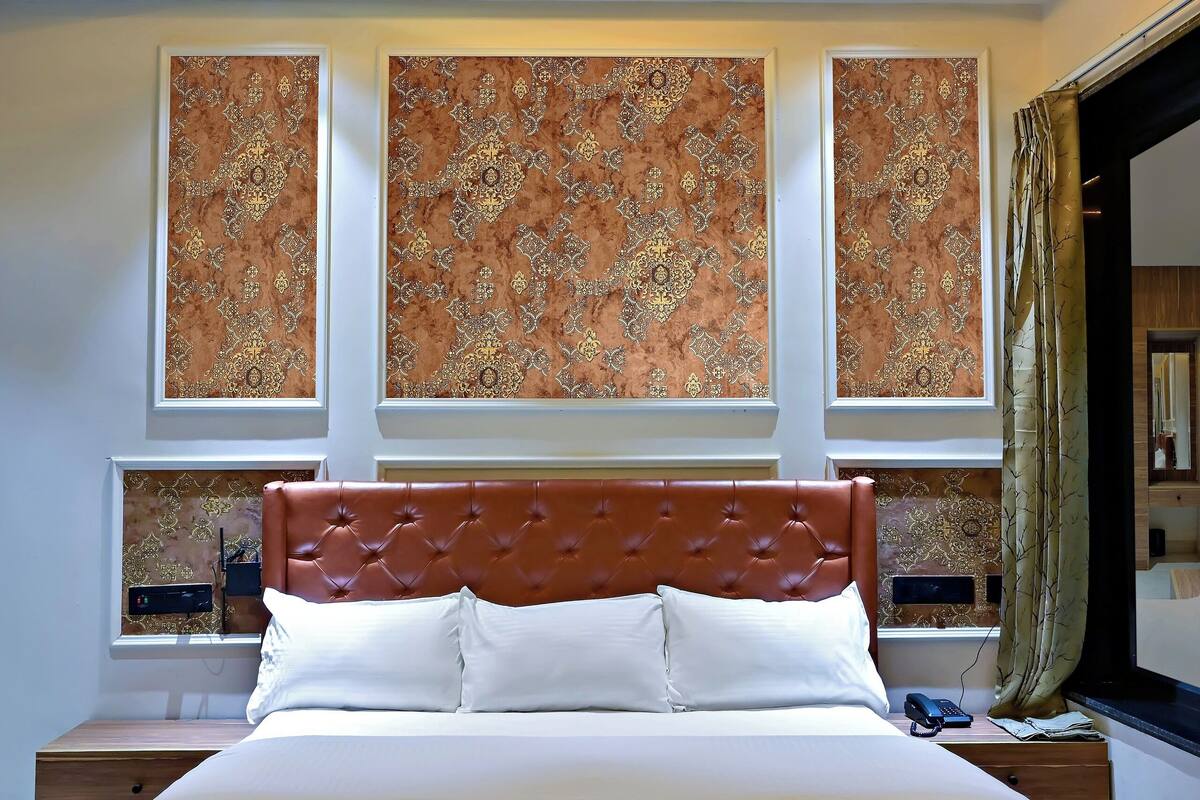 A modern bedroom with a bed, a ceiling fan, patterned wall decor, and a window with curtains.